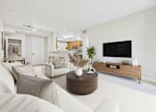 Thumbnail 16 of 53 - A modern living room with a white sofa and a wooden coffee table.