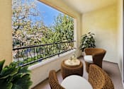 Thumbnail 22 of 53 - A balcony with a table and chairs overlooking a garden.