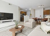 Thumbnail 36 of 53 - A living room with a white couch, a wooden coffee table, and a television.