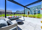 Thumbnail 161 of 163 - A patio with a couch and pillows under a black awning.