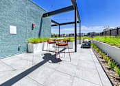 Thumbnail 160 of 163 - A patio with a table and chairs is in front of a green wall.