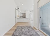 Thumbnail 43 of 163 - A long hallway with a rug on the floor and a glass door on the right.