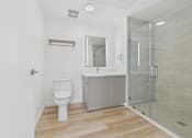 Thumbnail 76 of 163 - A white toilet sits in a bathroom with a walk-in shower.