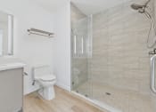 Thumbnail 61 of 163 - A white toilet sits in a bathroom with a walk-in shower.