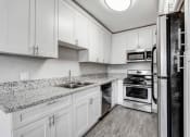 Thumbnail 21 of 52 - a kitchen with white cabinets and granite counter tops