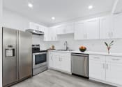 Thumbnail 19 of 52 - a white kitchen with stainless steel appliances and white cabinets