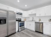 Thumbnail 28 of 52 - a white kitchen with stainless steel appliances and white cabinets