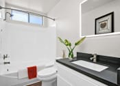 Thumbnail 18 of 22 - A white bathroom with a black counter top and a red towel.