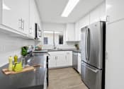 Thumbnail 1 of 22 - A modern kitchen with a stainless steel refrigerator and white cabinets.