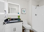 Thumbnail 20 of 22 - A white bathroom with a black countertop and a white toilet.