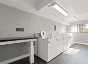 Thumbnail 6 of 8 - a laundry room with four washers and a row of washing machines