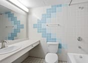 Thumbnail 26 of 92 - A white toilet sits in a bathroom with blue tiles.