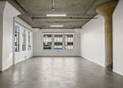Thumbnail 23 of 92 - A large empty room with a concrete floor and a large column on the right side.
