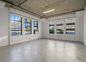Thumbnail 22 of 92 - A large empty room with three windows and a concrete floor.