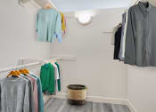 Thumbnail 11 of 16 - a walk in closet with clothes hanging on the wall