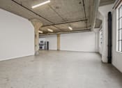 Thumbnail 11 of 92 - A large, empty room with concrete floors and walls, and a few pieces of furniture.