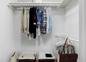 Thumbnail 15 of 61 - a closet with clothes hanging on a rack and two boxes on the floor