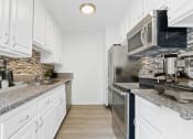 Thumbnail 10 of 20 - a kitchen with white cabinets and granite counter tops and stainless steel appliances