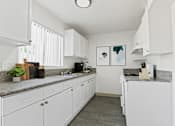 Thumbnail 1 of 8 - a white kitchen with granite counter tops and white cabinets