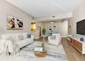 Thumbnail 4 of 26 - A living room with a white couch, a coffee table, and a painting on the wall.