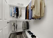 Thumbnail 7 of 26 - A white closet with clothes hanging and shoes on the floor.