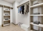Thumbnail 50 of 95 - a large walk in closet with shelves and a row of folded clothes