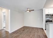 Thumbnail 22 of 23 - an empty living room with a ceiling fan and a kitchen