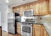 Thumbnail 27 of 88 - a kitchen with stainless steel appliances and wooden cabinets