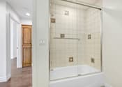 Thumbnail 56 of 88 - a white tiled bathroom with a tub and a shower