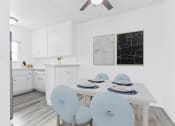 Thumbnail 3 of 23 - a white kitchen with a white table and blue chairs