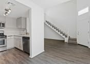 Thumbnail 23 of 94 - an empty kitchen and living room with white walls and wood flooring