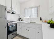 Thumbnail 1 of 23 - a white kitchen with stainless steel appliances and white cabinets
