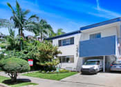 Thumbnail 25 of 25 - a white building with a blue roof and palm trees in front of it