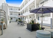 Thumbnail 30 of 45 - an outdoor patio with tables and chairs and umbrellas at a hotel