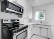 Thumbnail 10 of 73 - a kitchen with white cabinets and black appliances and a window