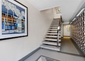 Thumbnail 22 of 25 - a staircase leading up to a hallway with a painting on the wall and a staircase