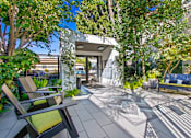 Thumbnail 17 of 25 - a patio with chairs and trees and a house in the background