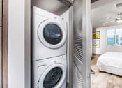Thumbnail 6 of 35 - A modern laundry room with a washer and dryer stacked on top of each other.
