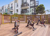 Thumbnail 29 of 40 - A wooden deck with three stationary bikes on it.