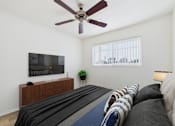 Thumbnail 5 of 50 - A living room with a couch, a television, and a ceiling fan.