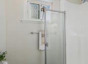 Thumbnail 34 of 79 - A glass door shower enclosure with a white towel rack and a small plant on the windowsill.