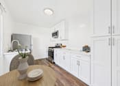 Thumbnail 36 of 41 - A kitchen with white cabinets and a wooden table.