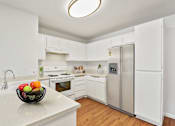Thumbnail 15 of 40 - a kitchen with white cabinets and a bowl of fruit on the counter