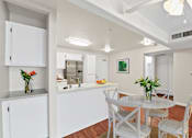 Thumbnail 6 of 40 - a dining area with a table and chairs and a kitchen in the background