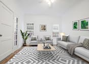 Thumbnail 1 of 32 - A living room with a grey couch, a coffee table, and a rug with a geometric pattern.