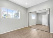 Thumbnail 61 of 62 - an empty bedroom with a mirrored closet door and a window