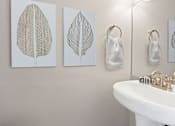 Thumbnail 9 of 24 - a bathroom with three paintings on the wall and a sink