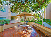 Thumbnail 22 of 33 - Resort-like picnic and barbecue area with wood bench, lush landscaping