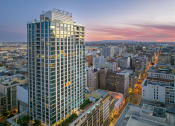 Thumbnail 44 of 45 - a cityscape with a tall skyscraper in the foreground and a sunset in the background