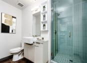 Thumbnail 8 of 45 - DTLA Apartments - Broadway Lofts - Bathroom With Modern Sink, Shelves, And Walk In Glass Shower With Tile